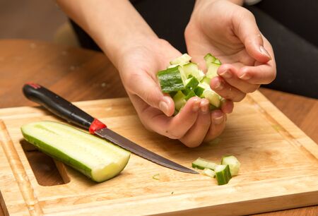 Slicing cucumber with a knife on the board .の写真素材