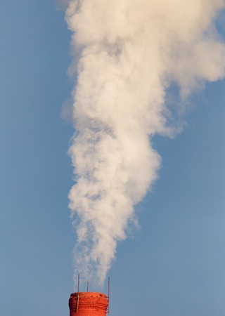 smoke from a pipe in the factory against a blue sky .の写真素材