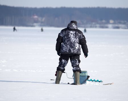 A man catches fish on ice in winter .の写真素材