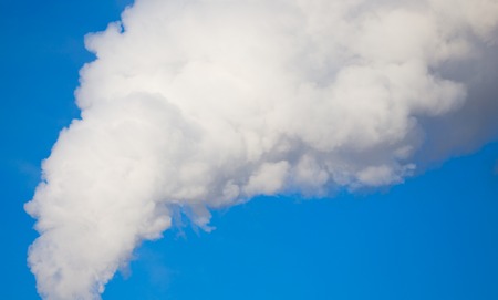 smoke from a pipe in the factory against a blue sky .の写真素材