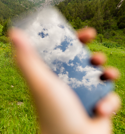 Clouds in reflection of a cell phone in handの写真素材