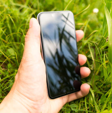 Grass in reflection of cell phone in hand