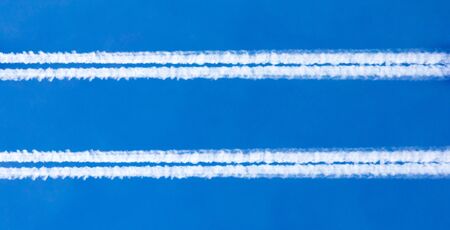 Traces of white smoke from an airplane on a blue skyの写真素材