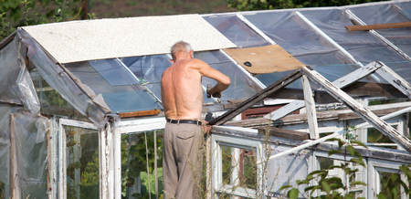 The old man works with a greenhouse in the countryの写真素材
