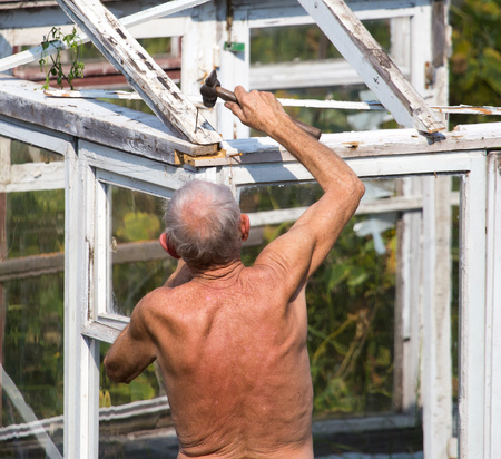 The old man works with a greenhouse in the country .の写真素材