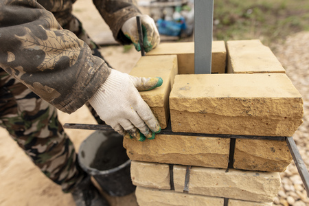 man builds a brick wall at a construction site .