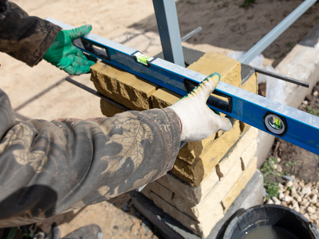 man builds a brick wall at a construction site .