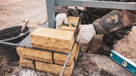 man builds a brick wall at a construction site .