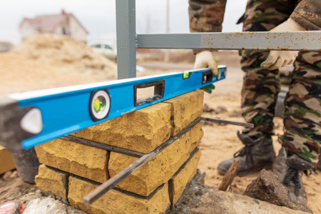 man builds a brick wall at a construction site .