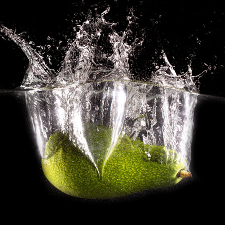 Green avocado in water on a black background .の写真素材