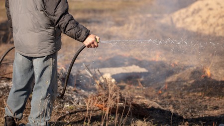 A man extinguishes the burning grass with water .の写真素材