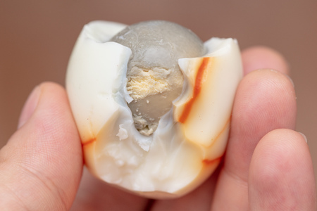 Boiled egg peeled and bitten in the hand .