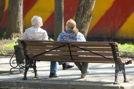 Two grandmothers are sitting on a park bench .の写真素材