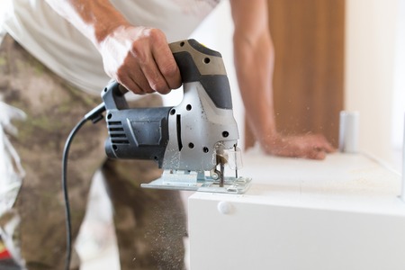 A man cuts out a wooden board with a jigsaw .の写真素材