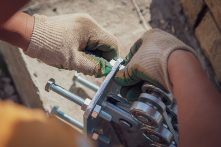 The worker installs rollers on the sliding gate .の写真素材