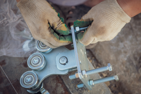 The worker installs rollers on the sliding gate .