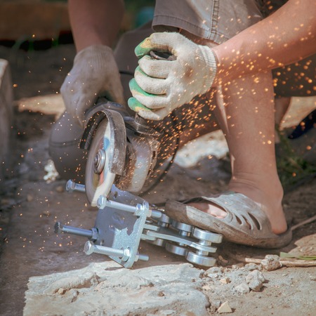 Worker cuts metal on a building site with sparksの写真素材