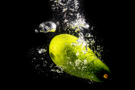 Green avocado in water on a black background .の写真素材