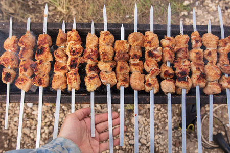 Meat roasted on sticks on charcoal in hand .の写真素材