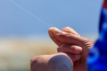 tying a line to a fishing pole .の写真素材