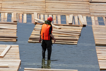 Workers build a dam of wood on the river .