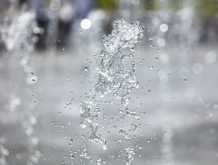 Splashing water from a fountain in the park as a background .の写真素材