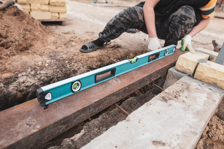The worker measures the length at the construction site .