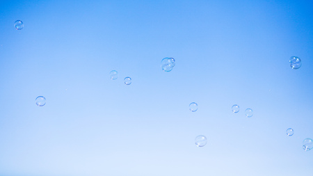 Soap bubbles in flight against the blue sky .