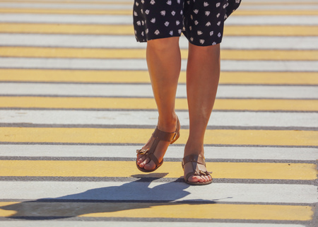 Legs of a girl crossing the road through a zebra .の写真素材