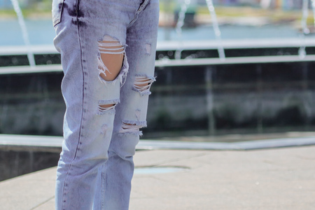 Legs of a girl in jeans with holes .