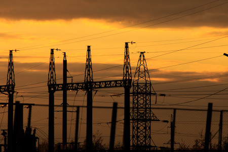 poles at a power plant at sunset as a background .