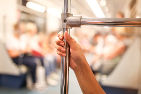 The girl's hand holds the handle in the metro .