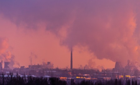 Smoke from the factory pipes against the dawn of the sun .