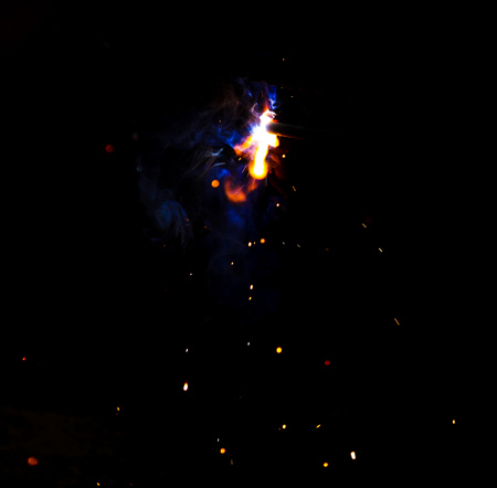 Flame of fire and sparks from welding metal at night .