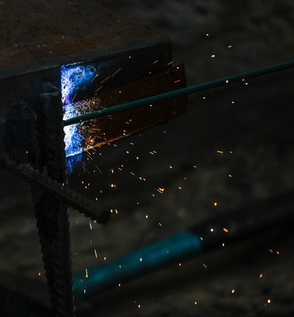 Flame of fire and sparks from welding metal at night .