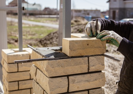 The worker is laying bricks on the fence .の写真素材
