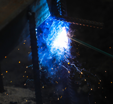 Flame of fire and sparks from welding metal at night .