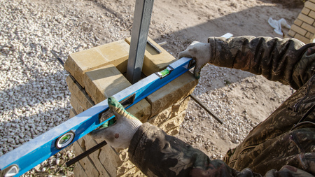 The worker is laying bricks on the fence .