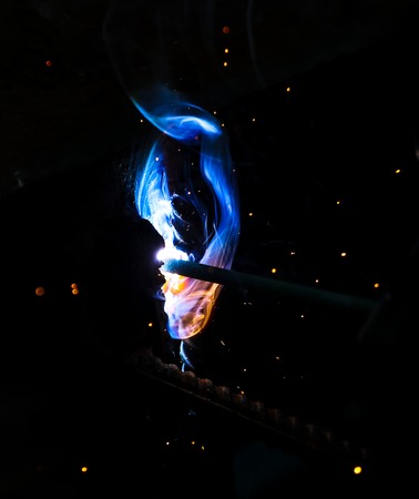 Flame of fire and sparks from welding metal at night .