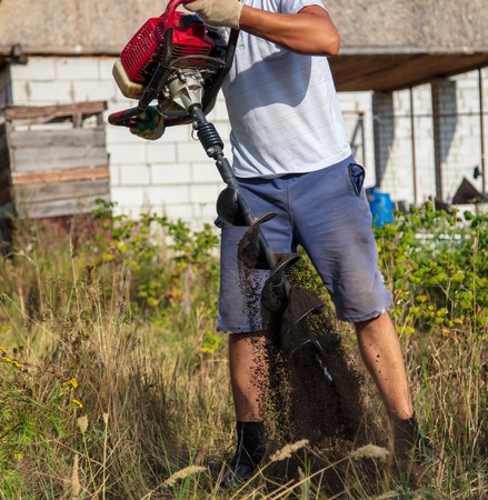 Worker drills the ground for the fence .