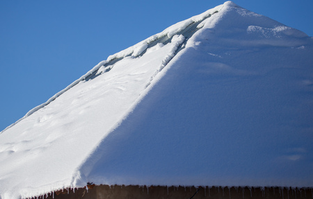 Snow on the roof of the house in winter .