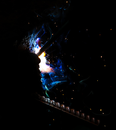Flame of fire and sparks from welding metal at night .