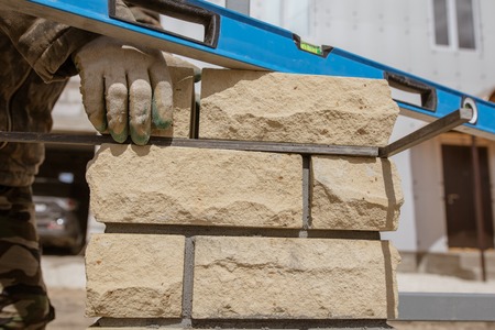 The worker is laying bricks on the fence .