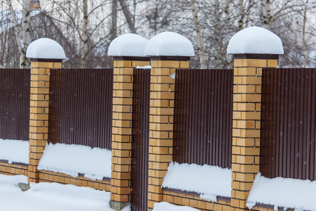 Snow on the fence of a country house in winter .の写真素材