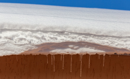 Snow on the roof of the house in winter .