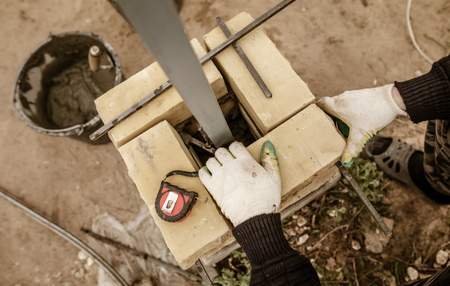 The worker is laying bricks on the fence .