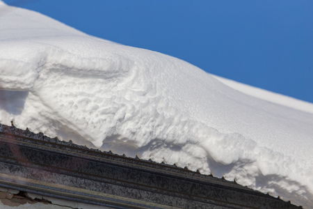 Snow on the roof of the house in winter .の写真素材