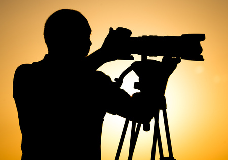 Man photographer with a camera at sunset .の写真素材