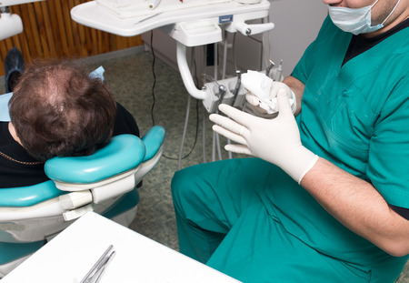 A dentist prepares an implant in the clinic .