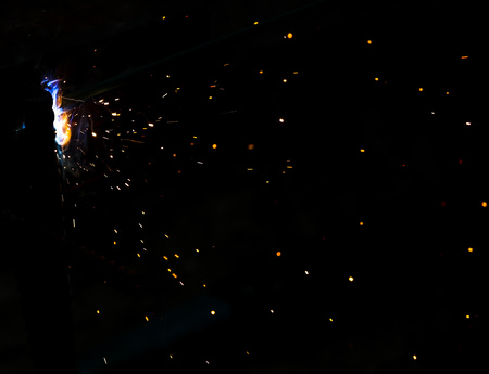Flame of fire and sparks from welding metal at night .